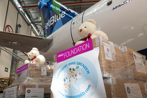 Airbus Foundation stickers on packages with teddy bears in front a jetBlue aircraft
