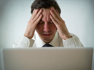 Man sitting at laptop, looking stressed