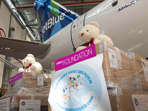 Airbus Foundation stickers on packages with teddy bears in front of a jetBlue aircraft
